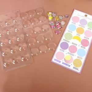 DIY craft kit with clear blister trays, colorful resin cabochons, and pastel sticker sheet.