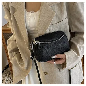 Detailed view of women's black leather crossbody bag featuring stylish double zipper design.