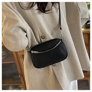 Detail shot of the black leather mini crossbody bag, featuring dual zippers and fine strap.