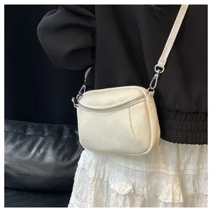 Close-up detail of white leather mini crossbody bag with double zippers and soft texture.