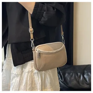 Close-up detail of genuine leather mini shoulder bag with double zipper and adjustable strap.