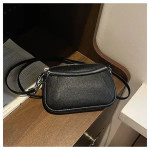 Detail shot of black leather crossbody bag, showing fine texture and zipper design.