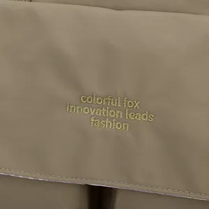 Gros plan détaillé d'un sac bandoulière en nylon kaki montrant une broderie fine.