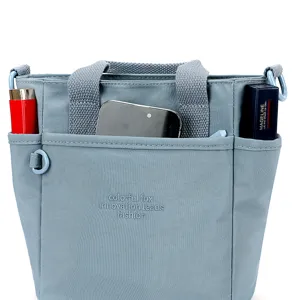 Vue détaillée du sac cabas bandoulière en nylon gris-bleu avec plusieurs poches pratiques.