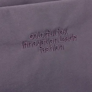 Vue rapprochée de la texture du tissu et de la broderie de marque du sac décontracté.