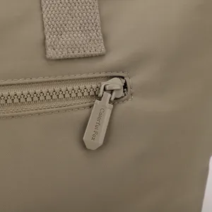 Détail de sac cabas de banlieue en nylon avec fermeture éclair en métal et tirette.