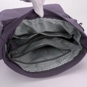 Purple crossbody shoulder bag interior detail showing multiple pockets and zipper lining.