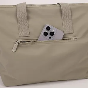 Gros plan détaillé sur la poche zippée avant du sac en nylon avec un smartphone.