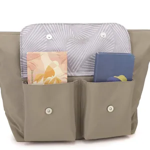 Détail de la poche avant du sac cabas en nylon gris avec fermeture à bouton-pression.