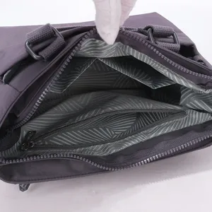 Détail intérieur du sac à bandoulière en nylon violet avec poches et fermeture éclair.