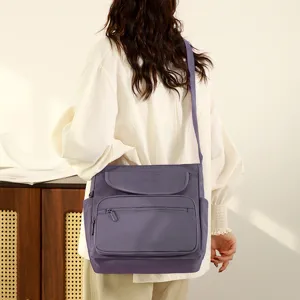 Detailed lifestyle view of a purple multi pocket crossbody shoulder bag worn by model.