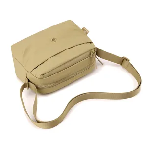 Detailed view of the lightweight multi-compartment nylon crossbody bag in khaki.