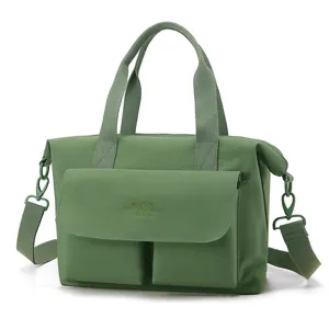Vue détaillée du sac cabas bandoulière élégant en nylon vert avec poches avant et poignées.