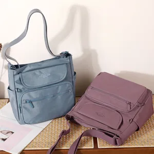 Detail shot of multi-pocket nylon crossbody shoulder bags in blue and purple, casual everyday style.