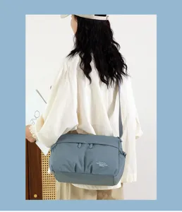 Casual blue nylon crossbody bag detail, showing strap and front zipper pocket design.