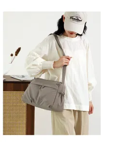 Casual grey nylon shoulder bag detail view, showing soft fabric texture and wide strap design.