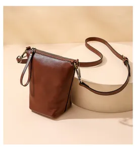 Detailed view of brown leather women crossbody bag with adjustable strap and metal hardware.