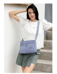 Detail shot of a light purple nylon crossbody shoulder bag, featuring multi-pocket utility design.
