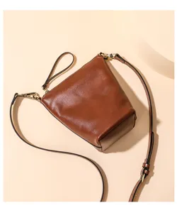 Detailed view of brown leather bucket bag, high texture and metal hardware, fashion crossbody.