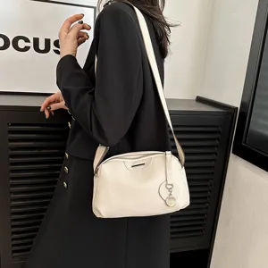 Detailed shot of a stylish beige leather crossbody bag with wide strap worn by a model.