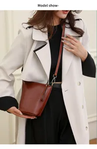 Detailed view of the stylish brown leather crossbody bucket bag worn by model in outfit.