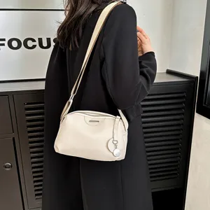 Detail view of minimalist cowhide crossbody shoulder bag with wide strap and zipper design.