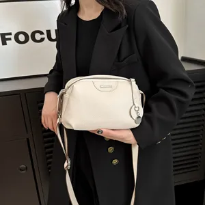 Close-up detail of genuine leather crossbody bag, soft texture, wide strap and metal zipper.