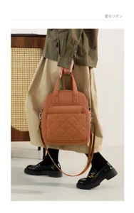 Detailed view of the brown nylon quilted backpack being held, showcasing durable fabric and design.