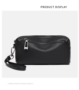 Black genuine leather women clutch bag detail, metal zipper and wrist strap feature.