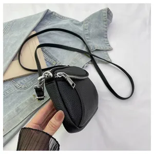 Close-up detail of black leather mini crossbody bag with double zippers and slim strap.