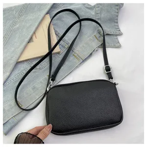 Black leather crossbody bag with double zippers and adjustable strap for daily use.