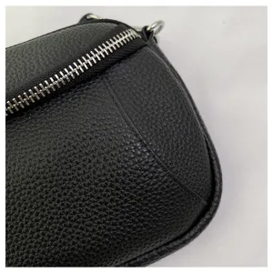 Black leather bag detail showing texture and zipper. Premium mini crossbody bag close-up.