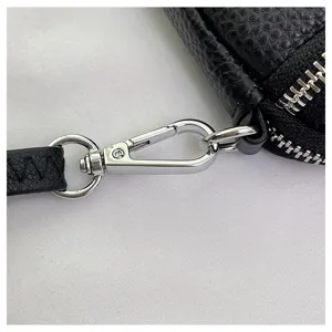 Close up detail view of black leather women bag hardware zipper and metal clasp strap accessory.