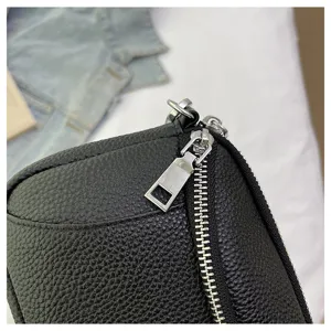 Close-up detail of black leather handbag featuring durable double silver zippers and fine texture.
