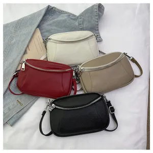 Detailed view of multi-color genuine leather crossbody bags with double zippers and straps.