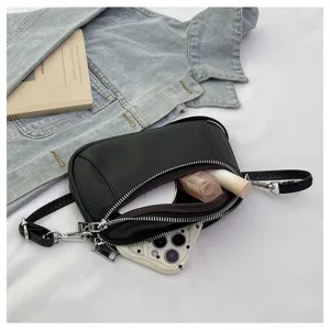 Detail view of black leather mini crossbody bag showing double zipper capacity and adjustable strap.
