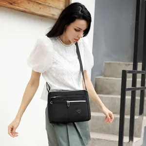 Detailed outdoor close-up shot of the black nylon crossbody bag worn by the model.