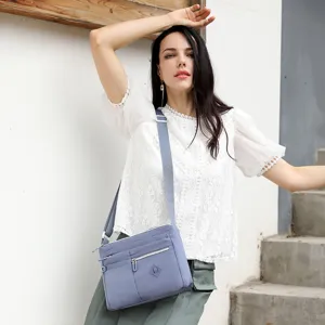 Detailed shot of a stylish grey-blue nylon crossbody bag with multiple zip pockets.