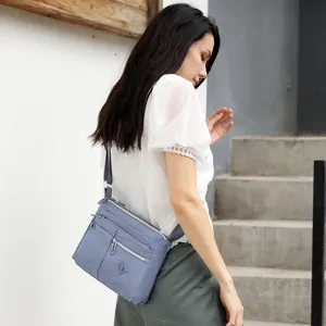 Detail view of women's nylon crossbody shoulder bag featuring multiple zipper pockets and sleek strap.