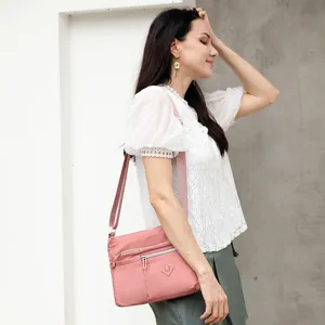 Womens pink nylon crossbody bag with multi zipper pockets for casual daily travel and shopping.