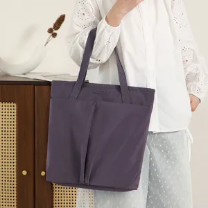 Detail view of lightweight nylon laptop tote bag in dark purple with dual handles and pockets.