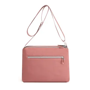 Pink nylon crossbody shoulder bag, water-repellent design with adjustable strap detail.
