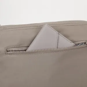 Close up detail of women nylon crossbody bag zipper pocket showing smooth fabric texture.