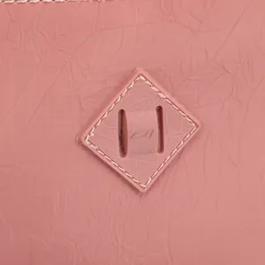 Close-up detail of pink nylon fabric and classic diamond lash tab accent for stylish bags.