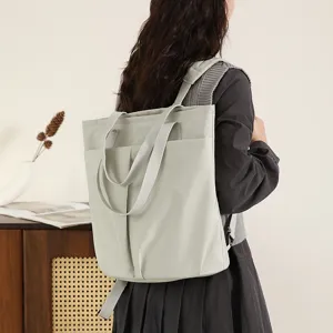 Detail view of light green waterproof nylon backpack with dual handles for daily commute.