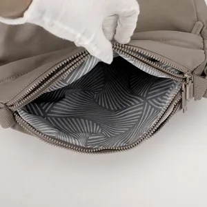 Close-up detail of the nylon shoulder bag interior lining, showing zipper and geometric pattern.