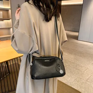 Black leather crossbody bag worn by model, showing wide strap and textured surface detail.