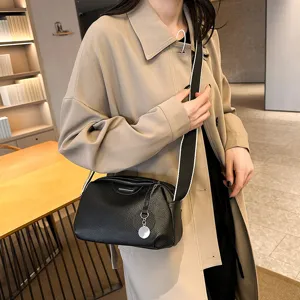 Detail view of black cowhide leather crossbody bag with wide strap, elegant daily accessory.
