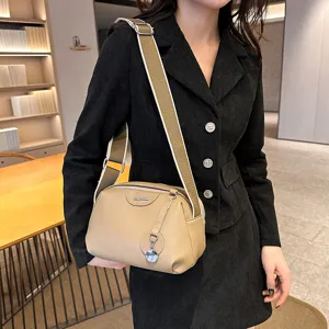 Detail view of stylish leather crossbody bag with wide strap, showing texture and hardware.