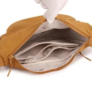 Close-up detail of yellow nylon crossbody bag interior, featuring multi-zipper compartments.
